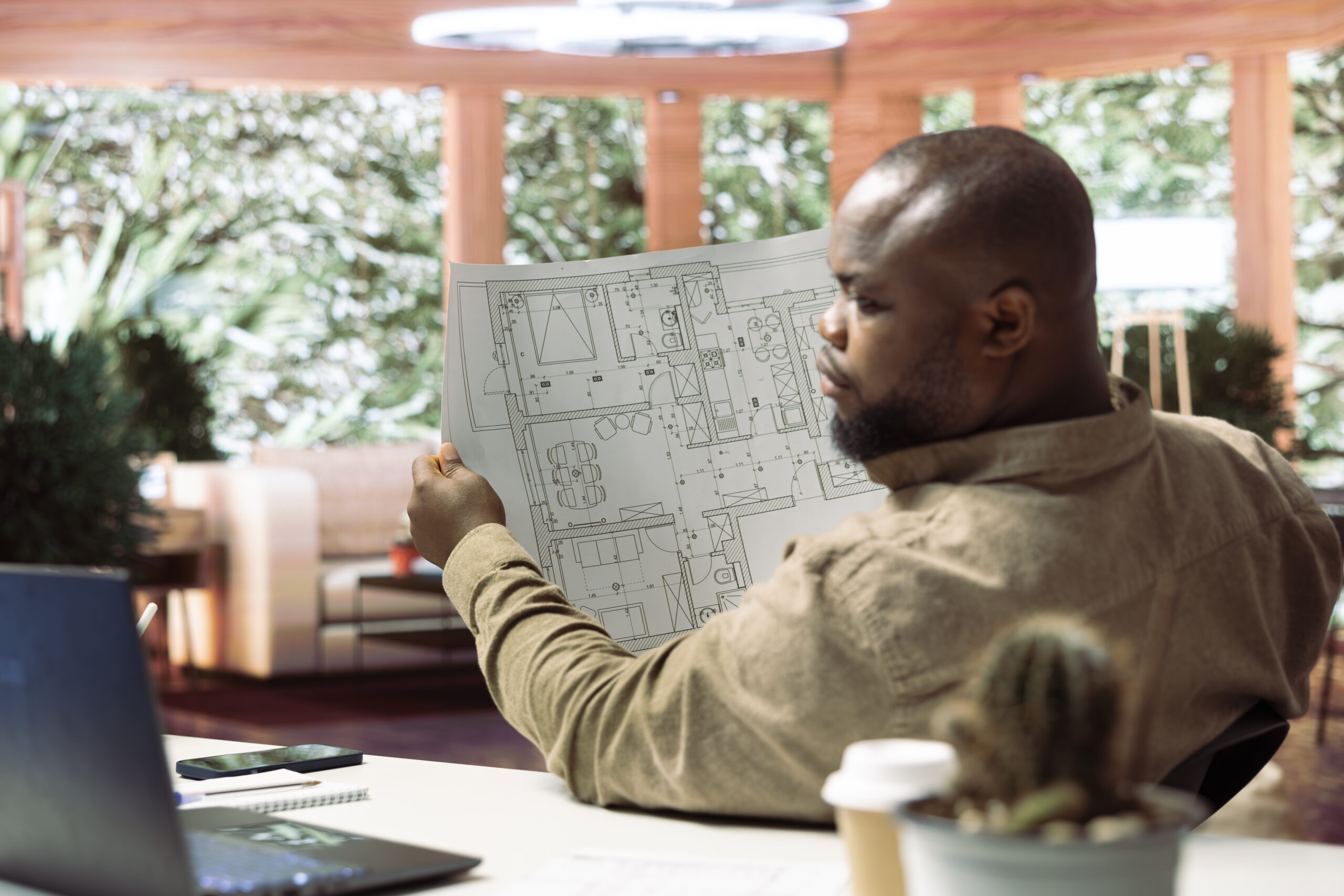 Small business owner analyzing architectural sketches and planning office spaces, focusing on blueprint review and strategic layout design. Evaluating property for modern and professional workspace.